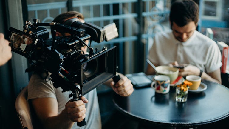 Cameraman filming a scene in a cozy cafe setting, capturing the cinematic atmosphere.